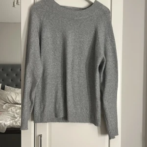 Grå stickad tröja från Vero Moda - Mysig grå stickad tröja från Vero Moda i storlek M. Tröjan har rund halsringning, ribbade muddar och lång ärm. Perfekt för lager-på-lager och enkel att matcha med jeans eller kjol.