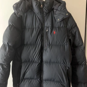 Svart dunjacka Polo Ralph Lauren XS - Svart dunjacka från Polo Ralph Lauren med huva och dragkedja framtill. den är xs men den är man så passar mig som brukar ha s/m