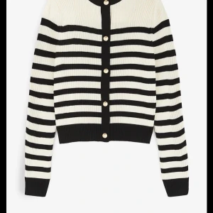 Randig kofta från H&M med knappar - Säljer en ribbstickad kofta från H&M i svart och vitt med klassiskt randigt mönster. Koftan har guldiga knappar framtill, rund halsringning och långa ärmar. Perfekt att slänga över en t-shirt för en snygg look.
