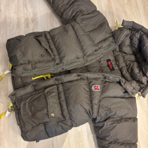 Grå dunjacka från Fjällräven - Säljer nu min gröna Fjällräven jacka. Den är i färgen Khaki. Strl Xxxs, men passar mig som är xs i vanliga fall. Använt skick, den är lagad på armen (se bild) och lagad vid en av fickorna ( se bild ) en fläck vid bröstet som säkert går bort på kemtvätt. Expedition modellen. Pris är diskuterbart  