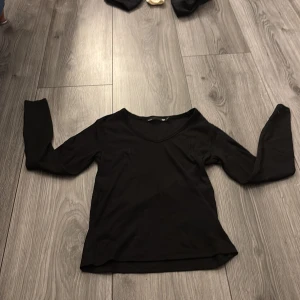 Svart ribbad långärmad topp 157 - Svart långärmad topp från 157 i storlek S. Toppen har v-ringning och är tillverkad i ett ribbat, stretchigt material som sitter snyggt på kroppen. Perfekt att styla med jeans eller kjol för en clean look.