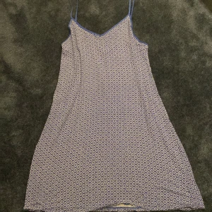 Blå mönstrad kortklänning Primark - Supersöt blå kortklänning från Primark med tunna axelband och ett ljust geometriskt mönster. Klänningen har en lätt A-linjeform och är perfekt för varma dagar. Materialet känns mjukt och svalt mot huden.