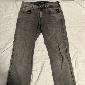 Replay Anbass - Snygga grå Replay Hyperflex jeans med klassisk femficksdesign och diskreta slitningar. Jeansen har raka ben och normal passform, tillverkade i stretchigt jeanstyg för extra komfort. Perfekta för dig som gillar stilrena och bekväma jeans.