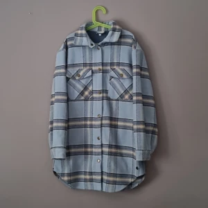 Blå rutig overshirt från Pomp de Lux - Overshirt i mjukt material från Pomp de Lux, blå och beige rutig med tryckknappar och två bröstfickor med lock. Långärmad och lite längre modell, perfekt att slänga över en hoodie. Klassisk krage och avslappnad passform.