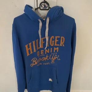 Blå hoodie från Hilfiger Denim - Blå hoodie från  Hilfiger denim i storlek M, modellen är ca 180cm. Hör av dig vid funderingar!