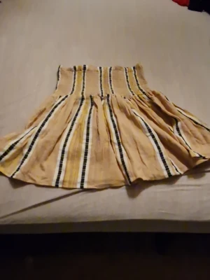 Randig kortkjol från Fine Copenhagen - Supersöt kortkjol från Fine Copenhagen i beige med svarta, vita och gula ränder. Kjolen har en smockad midja som ger en snygg passform och ett flowy fall. Perfekt för dig som gillar en avslappnad men trendig stil. Helt oanvänd, prislapp saknas. Priset kan diskuteras 🫶