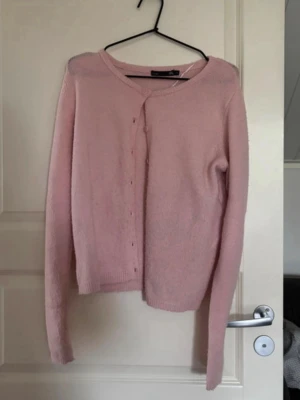 Ljusrosa kofta från 157 XS - Säljer en söt ljusrosa kofta från 157 i storlek XS. Koftan har rund hals, långa ärmar och knappar framtill. Materialet är mjukt och stickat, perfekt för lager-på-lager under kyliga dagar. Enkel och stilren design som funkar till många outfits.