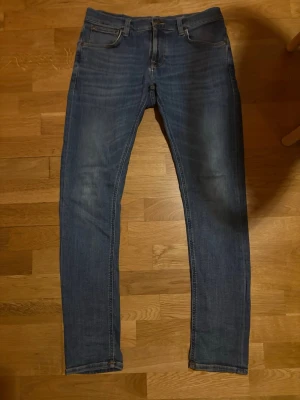 Tight Terry jeans Nudie - Blåa tight terry jeans från Nudie. Båda fickor har blivit lagade av auktoriserade Nudie parter, finns även väldigt små slitningar i grenen.