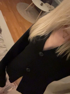 Svart trendig kofta ifrån Gina Tricot - Svart trendig kofta ifrån Gina Tricot med v-ringning och två stora knappar framtill. Jackan har långärmad design och är gjord i mjukt stickat material. Enkel och clean look som är lätt att matcha med olika outfits.är knappt använd så är i väldigt bra skick!den har inga defekter ba att it prislappen e kvar!