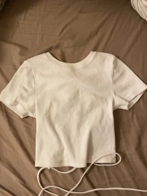 Vit topp - Vit topp med snörning baktill i storlek M men känns som S/XS. Säljer pågrund av att den ej kommer till användning, använd 1-2 gånger 🥰