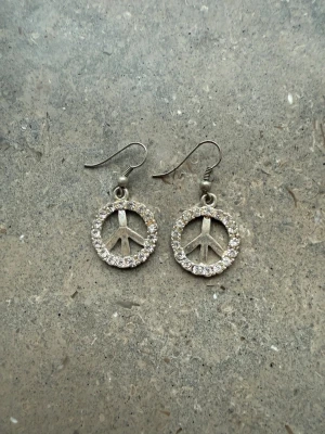Örhängen peace märke  - Silvriga örhängen men peace märke och stenar. Saknas någon sten 