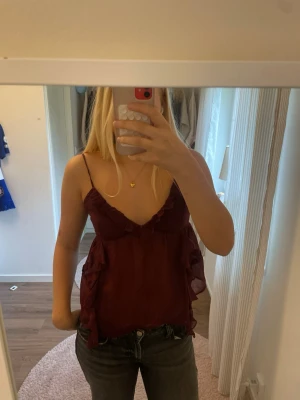 Vinröd volang topp  - En superfin vinröd topp med tunna justerbara axelband och volangdetaljer. Den är lite genomskinlig vid magen. Kom privat för frågor eller fler bilder!💕