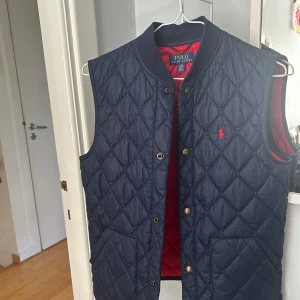 Mörkblå  väst från Polo Ralph Lauren - Quiltad väst i mörkblått från Polo Ralph Lauren med röd insida. Västen är väldigt snygg och ganska unik! Kontakta gärna vid frågor eller behov av fler bilder! Priset kan självklart diskuteras!🤝🏻💫