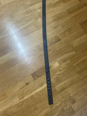 Svart rutig bälte - Säljer ett svart skärp från ett okänt märke med klassiskt rutigt mönster på framsidan och brun insida. Skärpet är tillverkat i skinn och har en stilren design som passar till jeans eller kostymbyxor. Perfekt för dig som gillar exklusiva accessoarer.