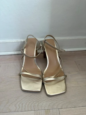H&M klackskor  - H&M klackskor i storlek 39.  Guldiga och så fina till fest eller bal.  Använda en gång och i fint skick, några få skavanker men endast på sulan så det syns inte utåt. 