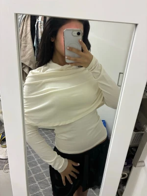 Vit långärmad omlottop - Säljer en vit långärmad topp med snygg omlott-detalj över axlar och bröst. Toppen har en tight passform och är tillverkad i ett mjukt, stretchigt material som sitter skönt på kroppen. 