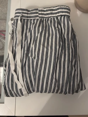 Randiga linnebyxor med snörning - Säljer ett par sköna linnebyxor med svartvita ränder och snörning i midjan. Perfekta för varma dagar och har en avslappnad passform. Materialet är lätt och luftigt, vilket gör dem riktigt bekväma att bära. Kan även användas som pyjamas byxor❤️