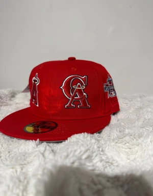 New era keps - Bilderna visar en röd keps med broderade MLB-loggor är lite mindre i storlek än vad de ska vara !