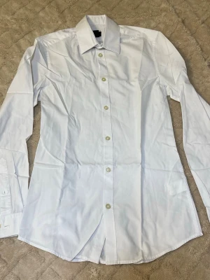 Vit skjorta från H&M XS - Klassisk vit skjorta från H&M i storlek XS. Skjortan har lång ärm, knappar framtill och en bred krage. Materialet är bomull och modellen är rak med normal passform. Perfekt för dig som gillar stilrena och enkla plagg.