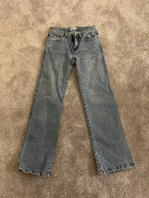  blå jeans bootcut - Säljer ett par jeans i ljusblå, modellen är 90’s boot. Jeansen har fickor, knapp och dragkedja fram samt detaljerade bakfickor med knapp. 