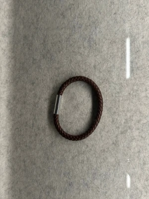 armband från Edblad - Snyggt brunt armband från Edblad med flätad design i skinn och ett stilrent magnetlås i silverfärgad metall. Perfekt accessoar för dig som gillar en enkel men cool look. Passar till både jeans och skjorta.