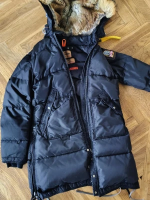 Svart dunjacka med päls från Parajumpers - Säljer en svart Parajumpers med äkta päls på huvan. Jackan är  SLM FIT  Medium Insidan är quiltad och fodrad med mjuk päls. Huvan är justerbar. En defekt på ena fickan annars i mkt fint skick
