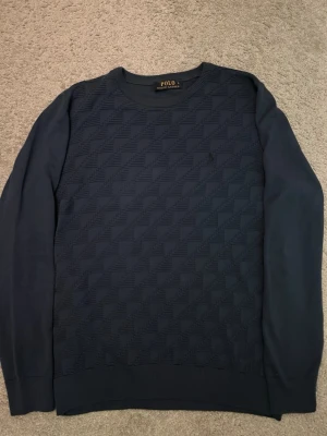 Mörkblå stickad tröja Polo Ralph Lauren - Säljer en mörkblå stickad tröja från Polo Ralph Lauren i storlek L men passar som M. Tröjan har ett diskret rutmönster på framsidan. Perfekt för en clean look. Tröjan är knappt använd och är i nytt skick