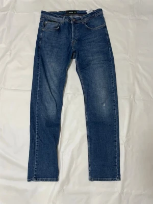 Slim fit jeans från Hugo Boss - Snygga blå jeans från Hugo Boss i modellen Glenn med slim fit-passning. Klassisk femficksdesign, knapp med Hugo Boss-logga och coola kontrastsömmar. Jeansen är tillverkade i bomull och har en fräsch, modern look som passar perfekt till sneakers.