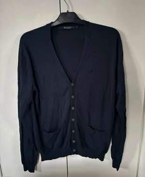 Tiger of Sweden kofta - Väldigt eftertraktad snygg marinblå Tiger of Sweden kofta i storlek L säljes. Perfekt nu till vintern och inga hål eller fläckar. Jättefint skick! Tveka inte vid minsta fråga eller fundering😊