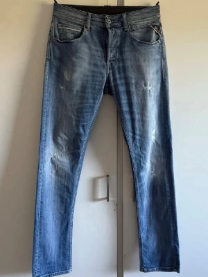 Replay Grover - Säljer ett par snygga Replay jeans i ljusblå tvätt med klassisk femficksdesign och raka ben. Jeansen har diskreta slitningar och detaljer vid fickorna, samt tydlig Replay-logga. Materialet är mjukt jeans och passformen är normal med midwaist.