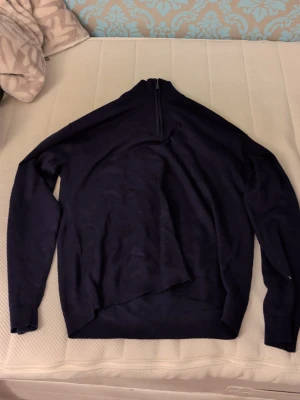 Mörkblå half zip tröja från Lindex - Säljer en mörkblå långärmad tröja från Lindex med half zip i halsen. Tröjan har en enkel och stilren design med ribbad krage och är tillverkad i mjuk bomull. Perfekt för dig som gillar klassiska och bekväma plagg.