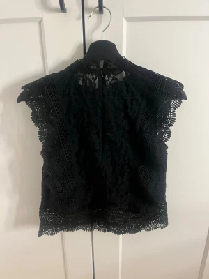 Svart spetsblus med detaljer - Säljer en svart blus från only med spetsdetaljer och rund hals. Säljer pga att jag inte hafft en stor användning av den, använt 2 gånger.