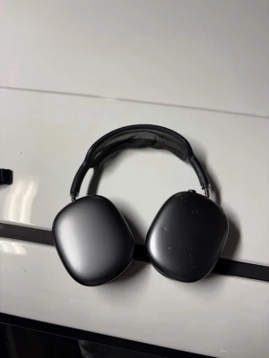 AirPods Max - Snygga svarta Apple AirPods Max med over-ear design och mjuka öronkuddar. Trådlösa hörlurar med aktiv brusreducering och hög ljudkvalitet. Några mindre ytliga märken syns på kåporna, men i övrigt gott skick. Perfekt för musik, film och samtal.