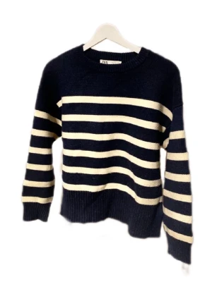 Marinblå och vit randig stickad tröja Zara - Säljer en snygg stickad tröja från Zara i storlek S. Tröjan är marinblå med breda vita ränder, har rund hals och långa ärmar. Ribbstickade muddar vid hals, ärmslut och nederkant. Perfekt för dig som gillar klassisk och chill stil.