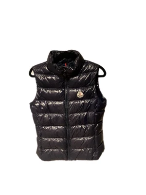 Mörkblå dunväst från Moncler - Säljer en mörkblå dunväst från Moncler med glansig finish och quiltad design. Västen har hög krage, dragkedja framtill och Moncler-logga på bröstet. Insidan har en unik serietidningsdetalj. Perfekt för lager-på-lager under kyliga dagar. Västen är i bra skick och passar en xxs-xs, låda medföljer.