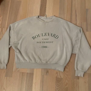 Vit tjocktröja med tryck - Jätteskön och fin oversized tjocktröja med grön text på framsidan, köpt från Nelly. Säljer då den tyvärr ej kommer till användning längre 💗