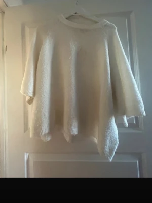 Vit stickad tröja från lager 157 - Mysig vit stickad tröja från lager 157 i storlek M. Tröjan har en loose passform med breda, trekvartsärmar och rund halsringning. Perfekt för lager-på-lager och chill dagar. Materialet är mjukt och fluffigt, vilket gör den extra skön att bära.