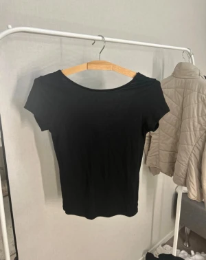 Svart T-Shirt med knytband  - Säljer en jättefin och vacker T-shirt från lager 157 i storlek xs som har en öppning i ryggen med ett rosettband som går att knyta och fixa hur man vill! Säljs då den ej kommer till användning!🥰 Djur och rökfritt hem, pris kan diskuteras!🫶🏻