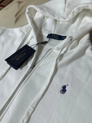 Vit Ralph Lauren zip hoodie - Denna tjocktröjan är helt ny och använd bara en gång! Inget fel med den och inga defekter. Storlek M och om du har mer frågor så är det bara att skriva till mig :)