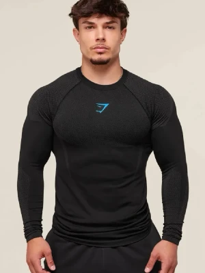 Svart långärmad Gymshark onyx  - Svart långärmad träningströja från Gymshark med blå logga på bröstet. Tröjan har tight passform, mesh-liknande struktur på axlar och ärmar samt är tillverkad i en blandning av nylon, polyester och elastan. Perfekt för gymmet eller annan träning.