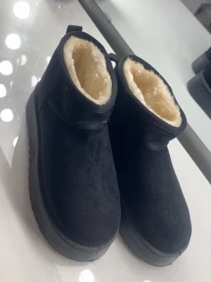 Uggs boot  - Mysiga svarta boots med fluffigt beige pälsfoder på insidan och grov sula för extra grepp. Utsidan är i mocka och de har en rund tå samt platt sula. Perfekta för kalla dagar när du vill hålla fötterna varma och sköna. Köptes på shein är helt nya men säljer då storleken är för stor på mig.