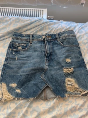 Blå jeanskjol från Zara  - Säljer en snygg blå jeanskjol med slitningar från Zara!