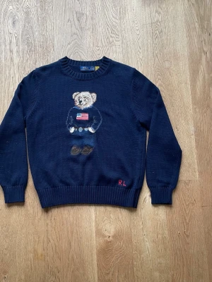 Mörkblå stickad tröja Polo Bear - .Säljer nu denna väldigt fina Ralph lauren tröjan i storlek S, då den inte kommer till användning. Den är i princip i nyskick endast använd 2 gånger. Den är marinblå med den ikoniska björnen broderad på tröjan. Material🧵100 % bomull Skick 9,5/10 Skickar samma dag. Tveka inte på att höra av er vid frågor.