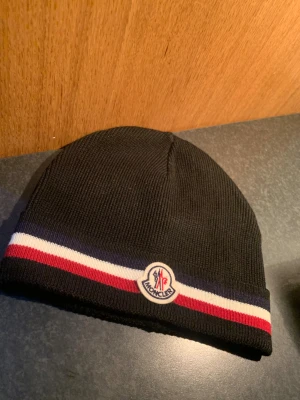 Svart Moncler mössa  - Svart tricolor mössa från Moncler med klassisk logotyp framtill.  Testad endast fåtal gånger, annars helt ny.  vid intresse så hör av er gärna ! 👍
