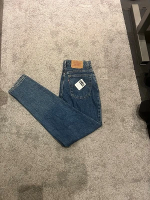 Levi's 551 blå jeans 29x33 - Klassiska blå Levi's 551 jeans med relaxed fit och tapered leg. Snygg vintagekänsla med ikonisk läderpatch bak och orange sömmar. Perfekta för dig som gillar en avslappnad stil och vill ha ett par tidlösa jeans i garderoben.