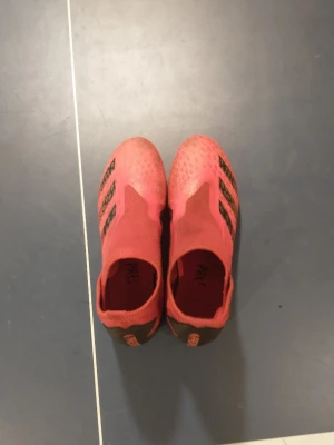 Adidas preditor fotbollsskor utan snören - Säljer ett par fotbollsskor från Adidas. Skorna har en passform utan snörning och dobbar i plast för bra grepp på planen. Materialet är syntet och designen är modern och sportig.