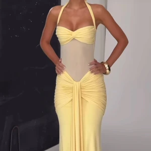 Gul långklänning med mesh och drapering - Supersnygg långklänning i ljusgul med halterneck och transparent mesh i midjan. Klänningen har draperade detaljer och markerad byst, samt en snygg knut framtill. Perfekt för dig som vill sticka ut med en unik och trendig look. Pris vid inköp: 1600kr