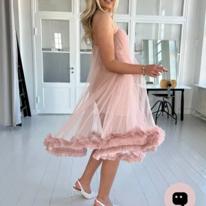 Ljusrosa axelbandslös tyllklänning - Superfin ljusrosa axelbandslös klänning i tyll med volangkant nertill. Klänningen har en luftig och flowy passform och är perfekt för dig som vill sticka ut med en romantisk look. Den är ärmlös och har en söt, feminin känsla med transparent lager över en kort underklänning. Köpte den för över 1200kr (med fraktkostnad) 😊 säljer den för fast pris 950kr ❤️ skick: som ny (endast testad) 