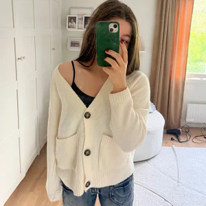 Krämvit kofta från Vero Moda - Supermysig krämvit kofta från Vero Moda med stora knappar och två rejäla fickor framtill. Använd en gång så koftan är som nytt skick!