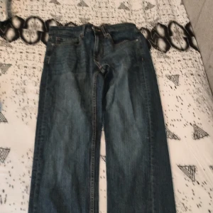 Blå jeans från Lee, midja 28/32 - Klassiska blå jeans från Lee med raka ben och normal passform. Jeansen har fem fickor, orange kontrastsömmar och läderpatch bak i midjan. Tillverkade i slitstarkt denim av bomull. Perfekta för dig som gillar en tidlös look. Det är perfekt till dig som vill göra om jeans de sitter perfekt jag som tjej kan ha på mig dem men kan även men killar kan även ha nu killar kan även ha den
